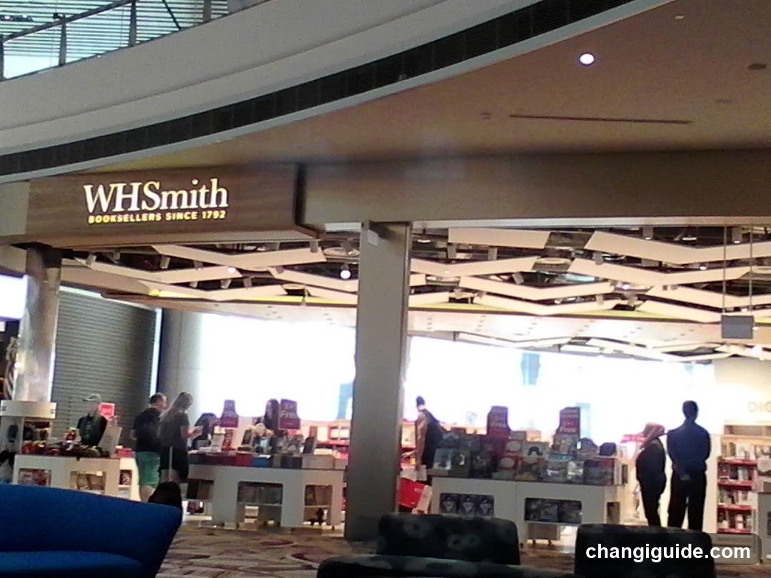 Photo of WHSmith bookstore entrance with visible signage reading 'WHSmith Booksellers since 1792'. Interior shows book displays, customers browsing, and modern ceiling design.