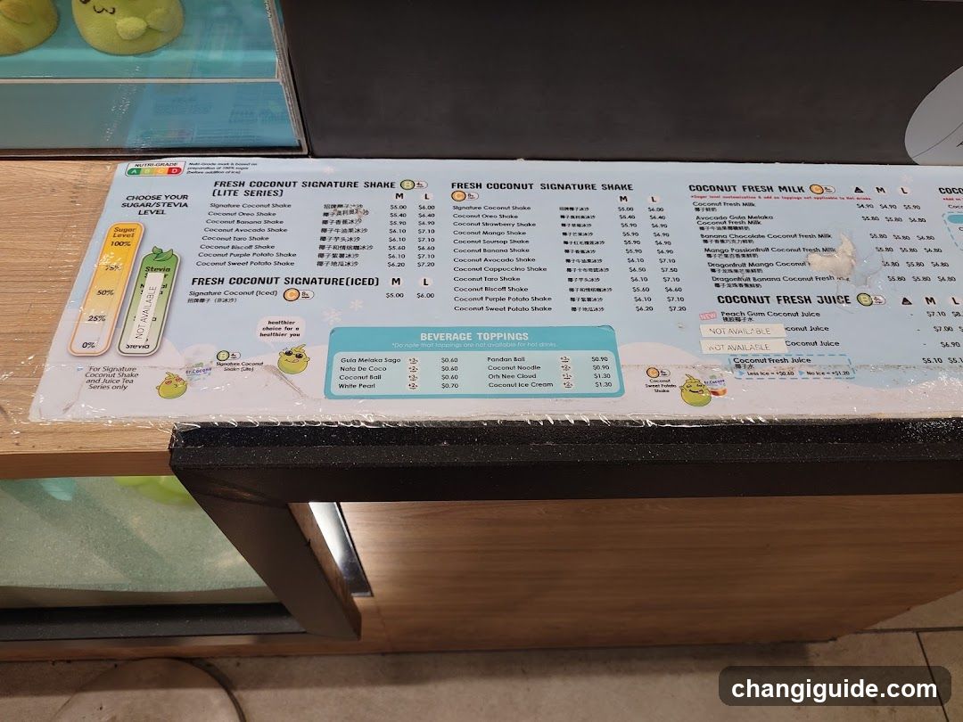 A close-up of a printed menu board on a counter, featuring sections for 'Fresh Coconut Signature Shake', 'Coconut Fresh Milk', and 'Coconut Fresh Juice'. The menu lists various shake flavors with prices in USD (e.g., $4.06, $5.19) and includes a 'Beverage Toppings' section.