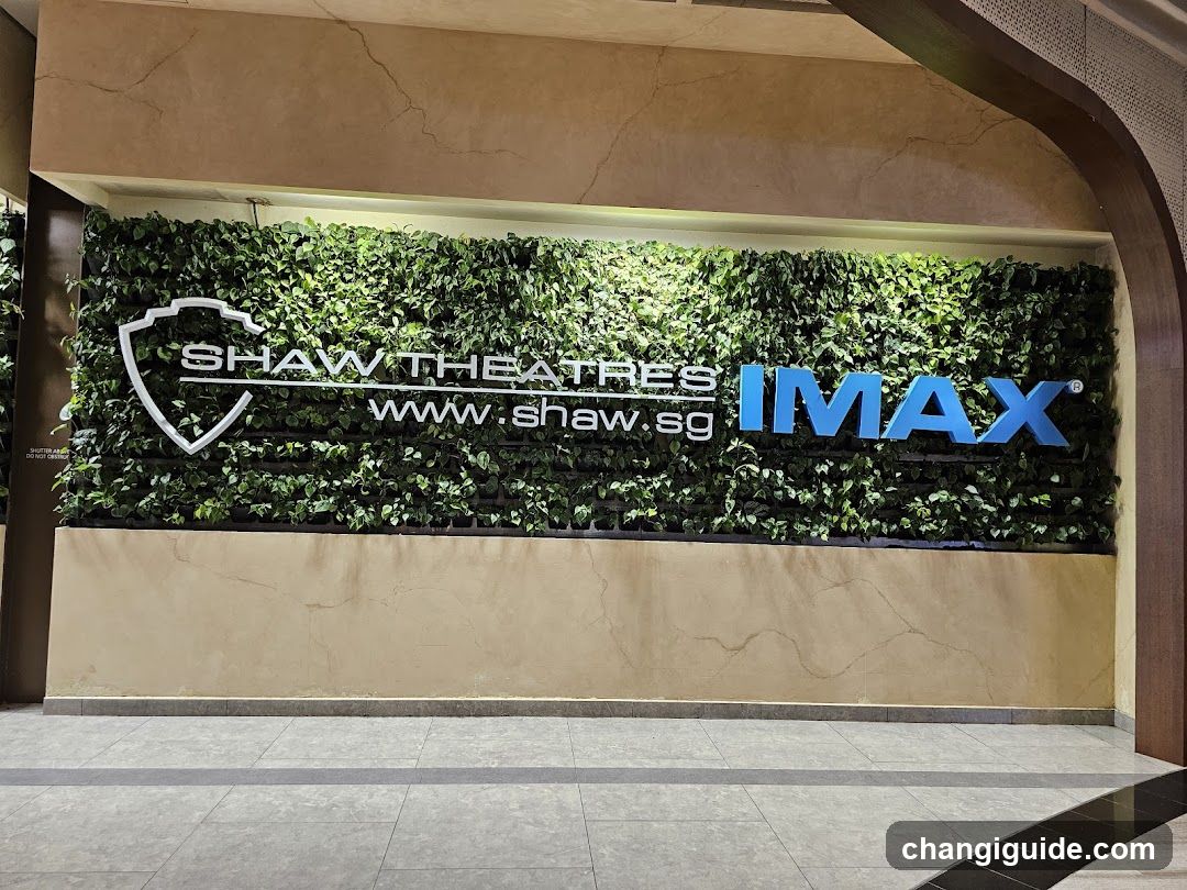 A wall-mounted sign featuring the Shaw Theatres logo and website URL, alongside a large blue IMAX logo, set against a green living wall backdrop inside a modern building entrance.