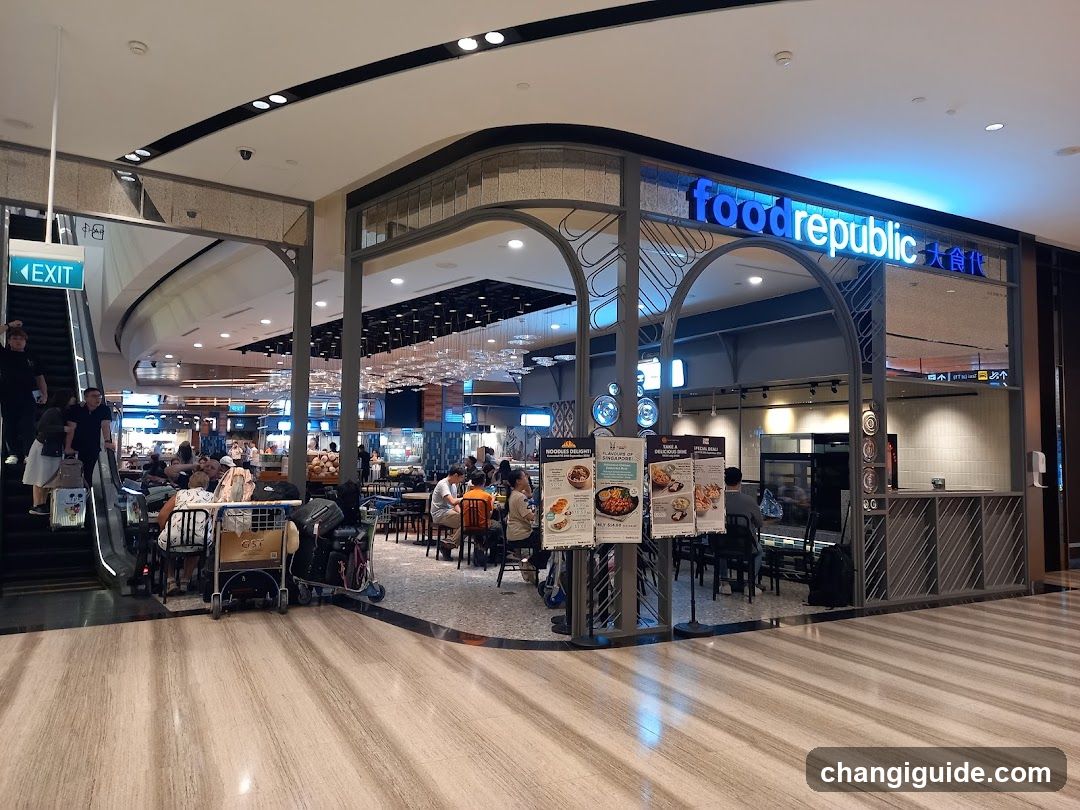 A modern food court entrance with arched metal framing and illuminated signage reading 'food republic' in blue LED letters alongside Chinese characters. Inside, diners sit at tables under hanging lights; an escalator leads upward to the left. Menu boards stand outside near the entrance.