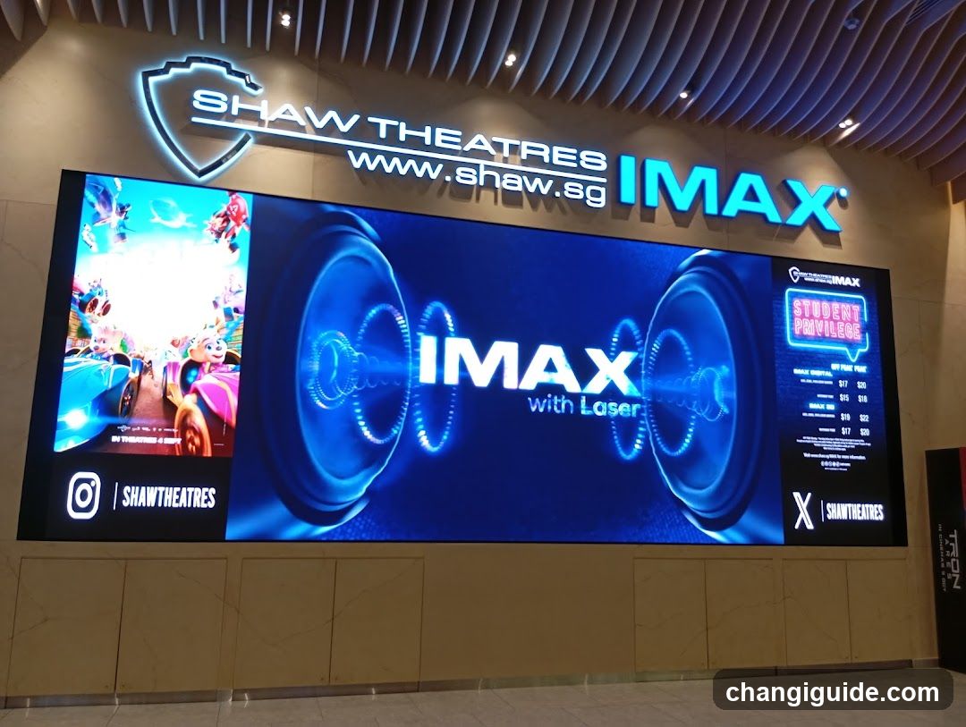 A brightly lit storefront entrance featuring a large illuminated sign reading 'SHAW THEATRES' with the website URL and 'IMAX' branding below it. A prominent digital display showcases an IMAX advertisement with laser technology visuals, alongside promotional pricing details on the right side. The Instagram handle '@shawtheatres' is visible at the bottom left of the screen.