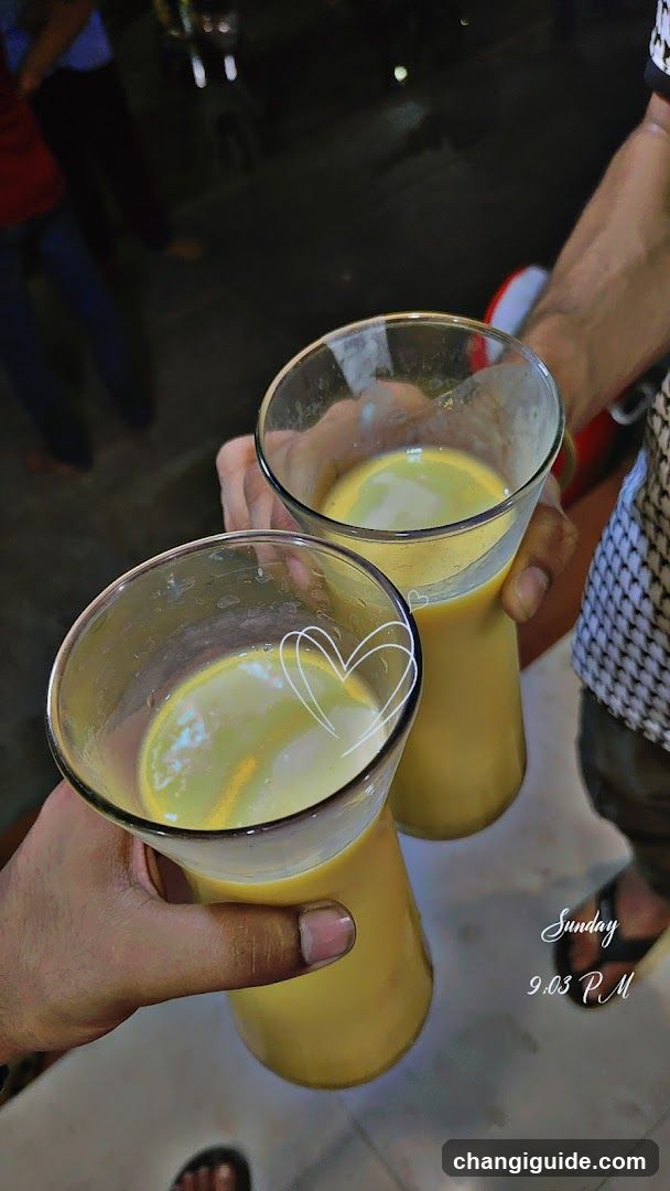 Two glasses of yellow drink being held up