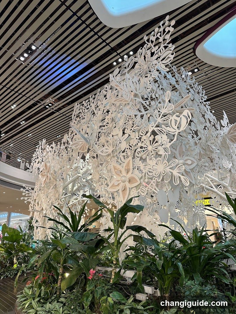 White floral sculpture display with greenery