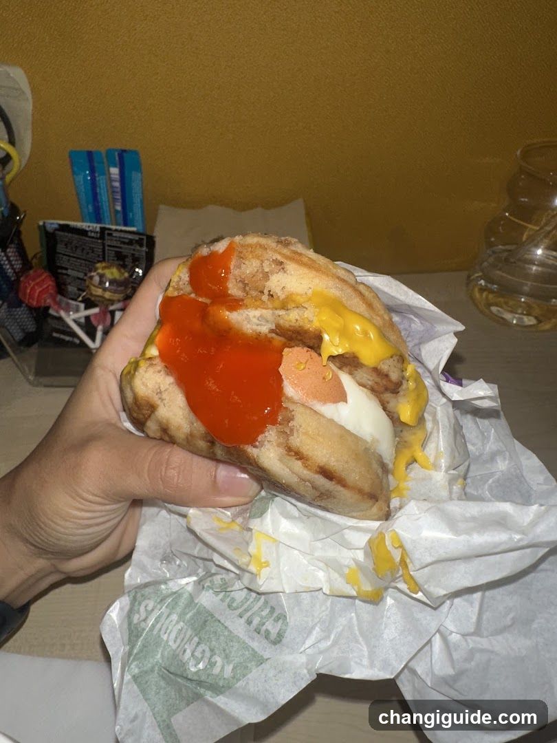 Hand Holding a Loaded Sandwich with Ketchup and Mustard