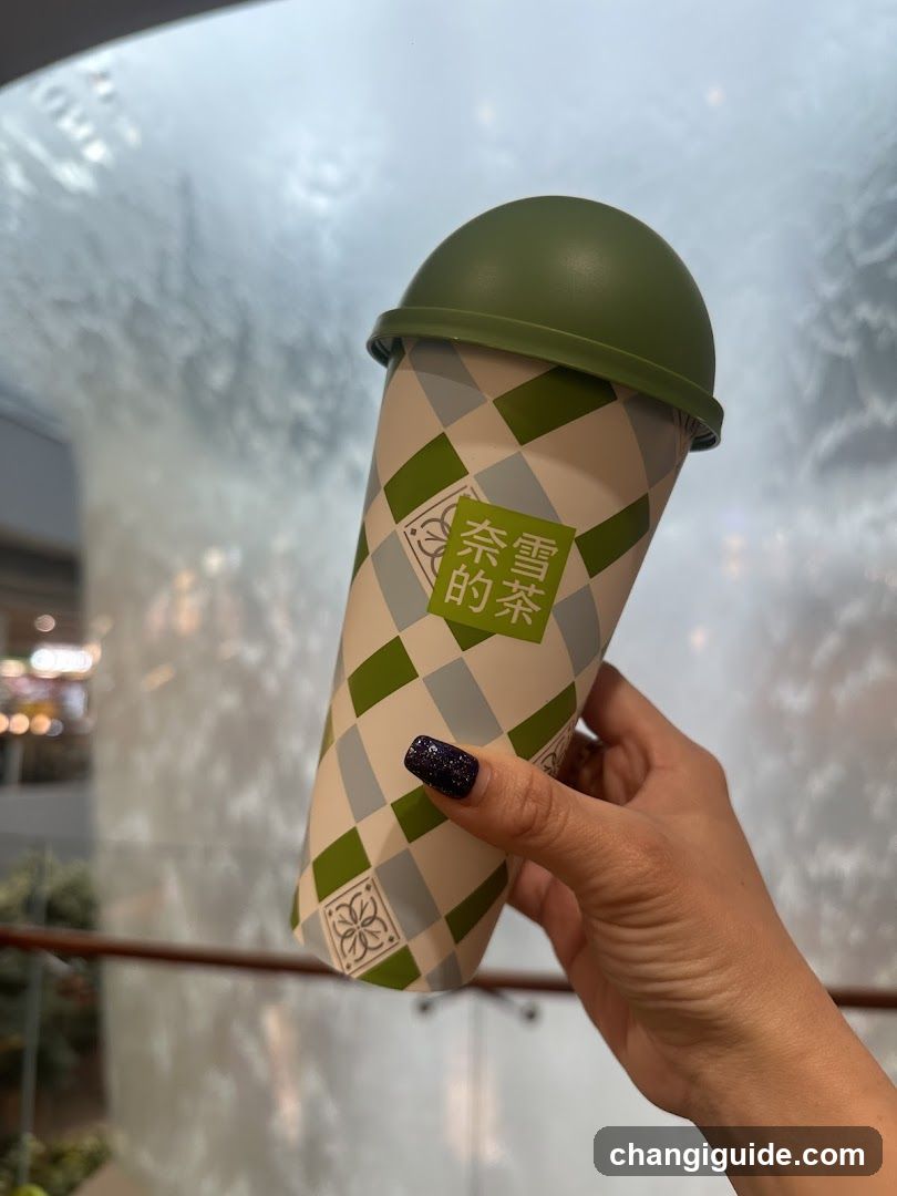 Hand holding a green and white checkered cup with Chinese characters