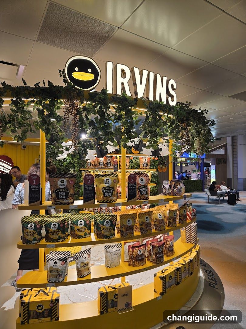 A vibrant yellow display stand featuring various snack products, including 'Irving's' branded items like 'Waffle Crunch', 'Crispy Corn', and 'Peanut Butter'. The stand is adorned with greenery and illuminated signage displaying the brand name 'IRVINS' above. Shoppers are visible in the background, browsing nearby.