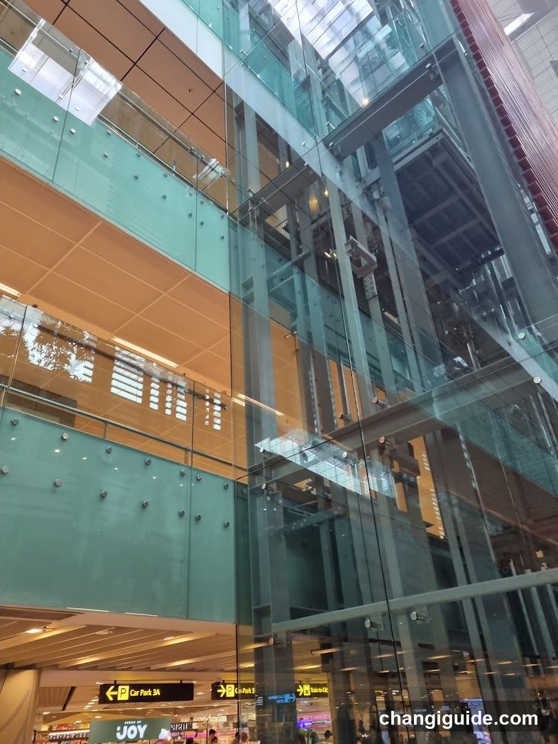 Interior of a modern building with glass elevators and signage