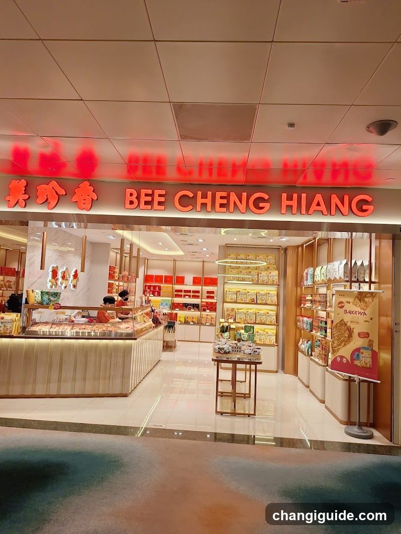 The image shows the storefront of a Bee Cheng Hiang shop, featuring bright red signage with both Chinese characters and English text. The entrance is well-lit, showcasing glass display cases filled with products inside. Inside, shelves are stocked with packaged goods, and promotional posters are visible near the entrance.