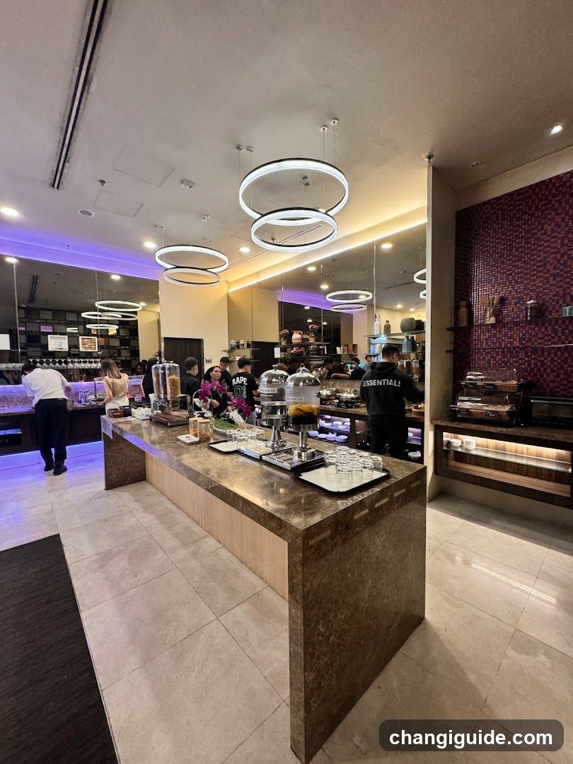 A modern hotel or restaurant buffet area with a marble counter, serving dishes under glass domes, staff in black uniforms, and ambient lighting including circular pendant lights.