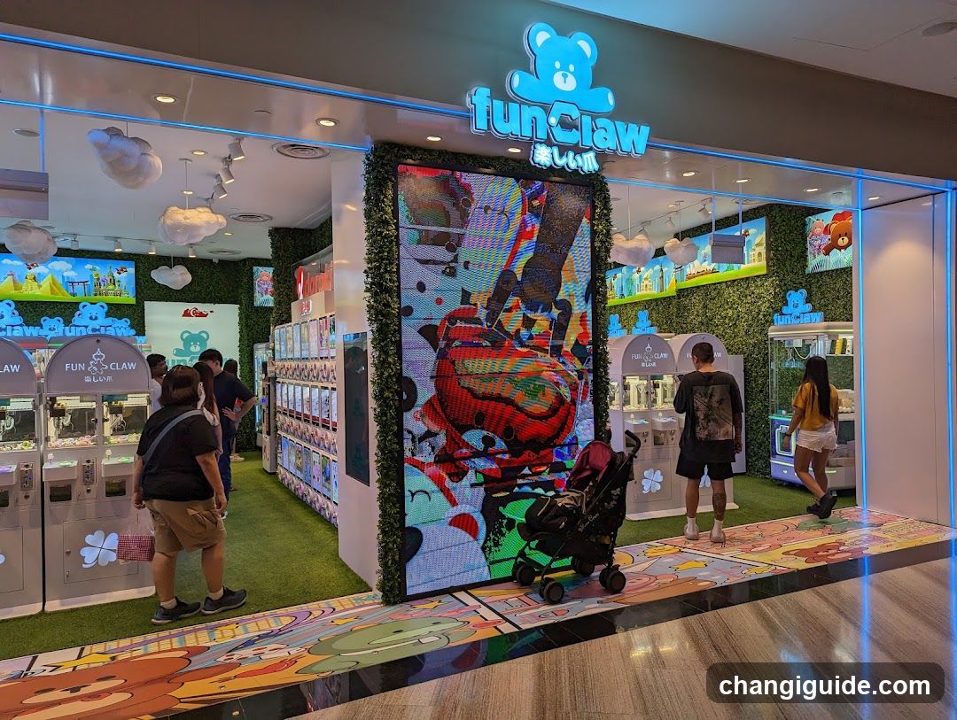 The image shows the exterior entrance of a funClaw store, featuring bright blue neon signage with a bear logo above the entrance. The storefront is decorated with greenery and colorful artwork on the walls. Several claw machines are visible inside, along with customers browsing and interacting with the games. A stroller is parked near the entrance, indicating family-friendly activity.
