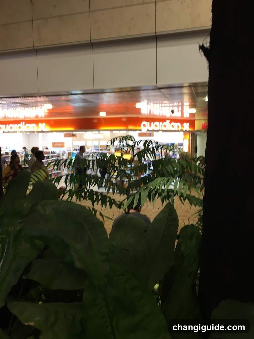 A view through green foliage into a well-lit store interior with visible signage reading 'guardian'. Shelves stocked with products and customers browsing are seen in the background.