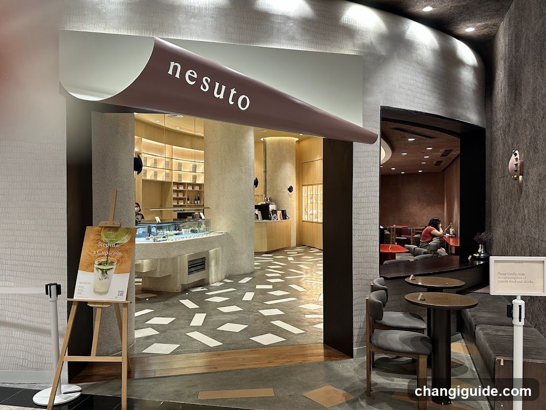 Interior of nesuto cafe showing counter, seating area with tables and chairs, and a menu board on an easel outside the entrance.