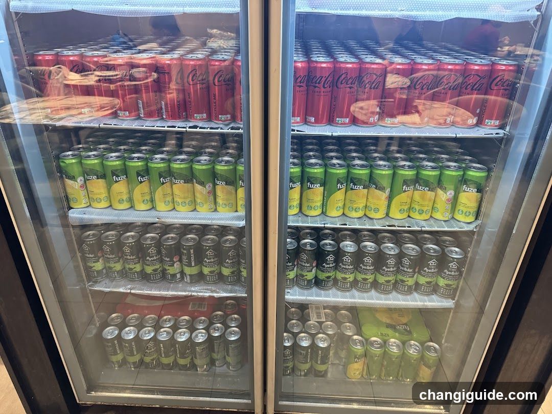 A double-door glass refrigerator stocked with various canned beverages, including Coca-Cola and Fuze tea varieties.