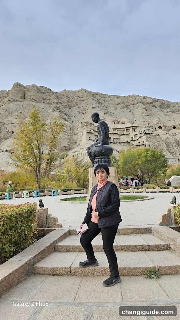 Woman posing in front of a statue and cave complex