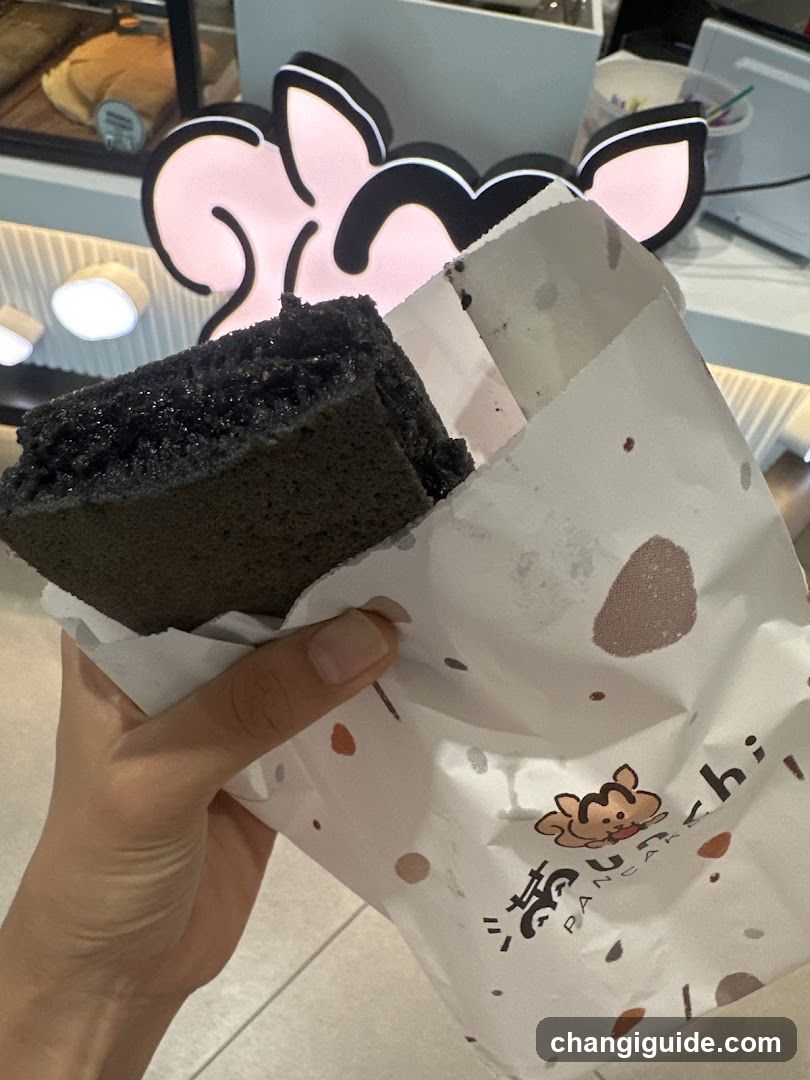 Hand holding a dark cake in branded paper bag