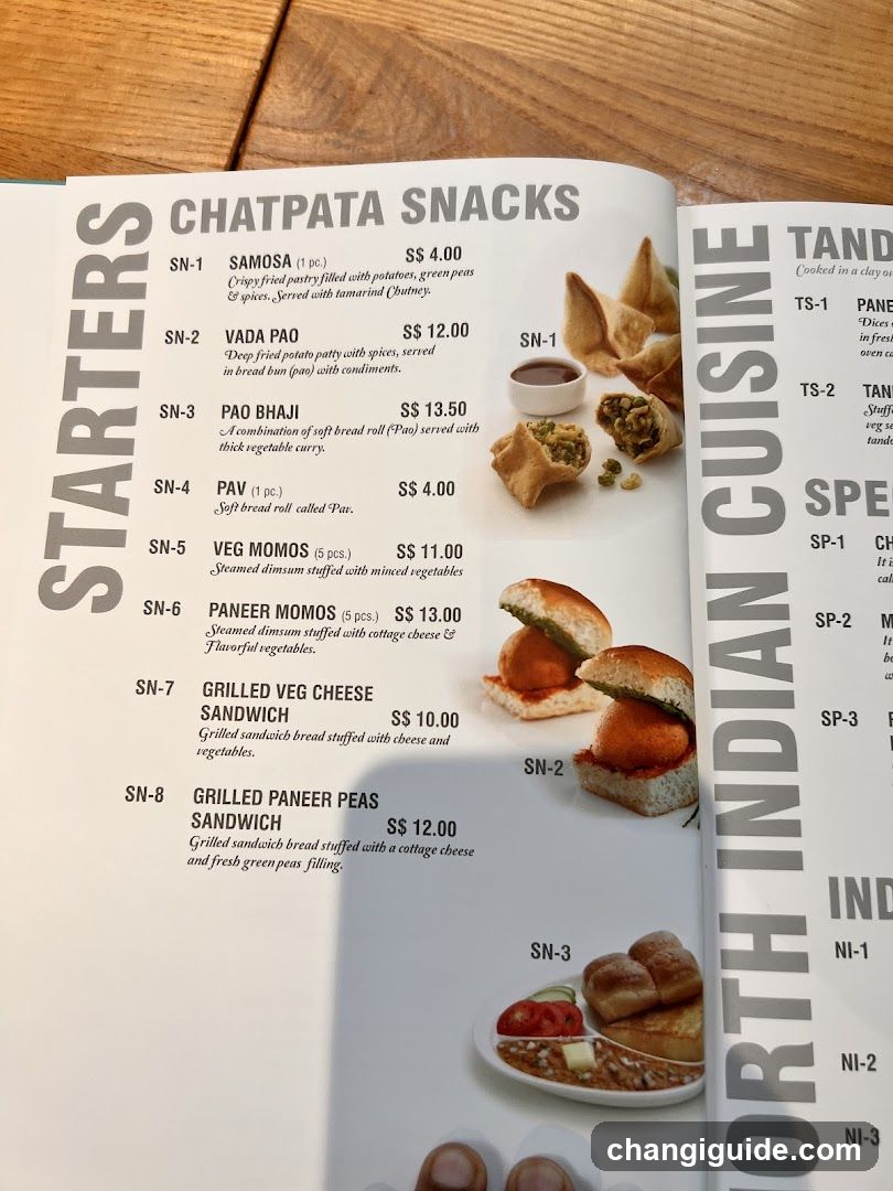Open menu page displaying Indian snacks under 'Starters' and partial view of 'North Indian Cuisine'. Includes items like Samosa, Vada Pao, Paan Bhaji, Veg Momos, Paneer Momos, Grilled Veg Cheese Sandwich, Grilled Paneer Peas Sandwich.