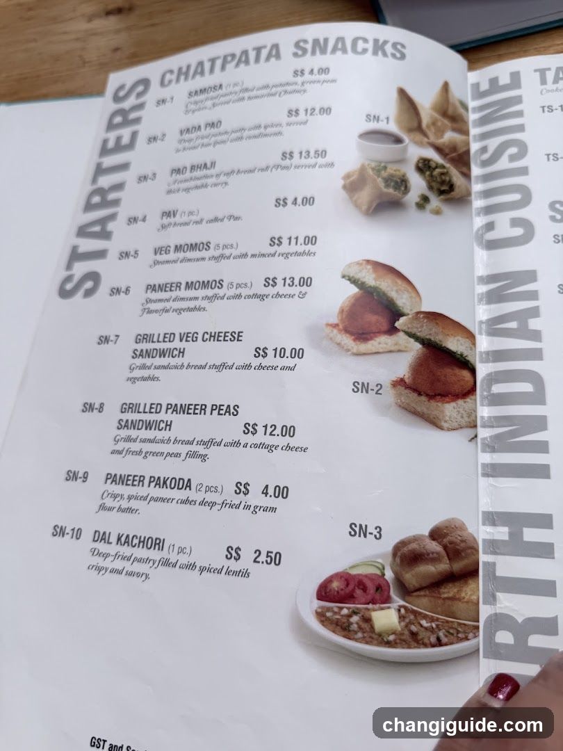A printed menu page featuring North Indian cuisine snacks, including Samosa, Vada Pav, Paneer Bhaji, and others with prices in SGD.