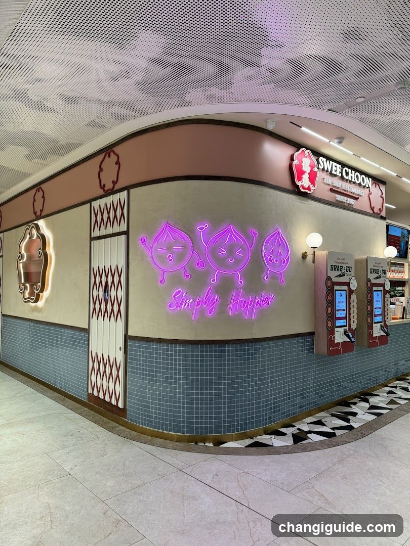 A brightly lit storefront with a curved facade featuring neon pink signage reading 'Simply Happier' alongside cartoon fruit characters. Above, the brand name 'SWEE CHOON' is displayed in red and white lettering on a dark background. The wall has decorative patterns including diamond motifs and tiled sections at the base. Two self-service kiosks are mounted to the right of the entrance.