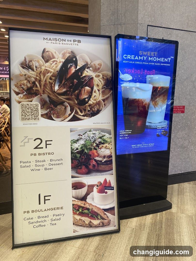 A promotional standee featuring Maison de PB by Paris Baguette, showcasing dishes like seafood pasta and sweet creamy moment drinks. The sign lists offerings on 2F (PB Bistro) including pasta, steak, brunch, salad, soup, dessert, wine, and beer. On 1F (PB Boulangerie), it highlights cake, bread, pastry, sandwich, salad, coffee, and tea.