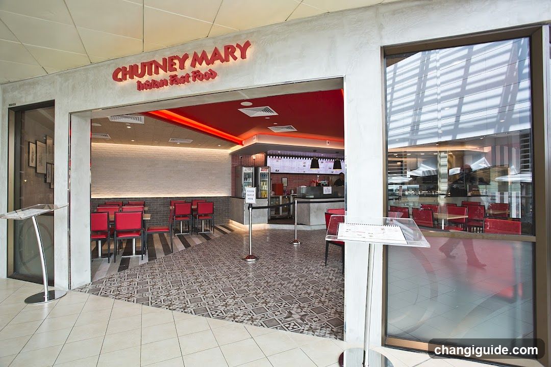 Entrance to Chutney Mary, an Indian fast food outlet with red signage above the doorway. Interior shows red chairs and tables, a counter area, and patterned flooring.