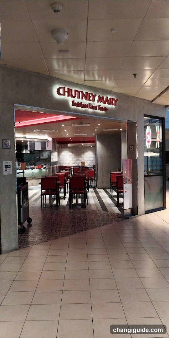 Entrance to Chutney Mary, an Indian East Food restaurant with visible signage above the doorway. Interior shows red chairs and tables arranged in rows, a kitchen area in the background, and tiled flooring extending into the shop.