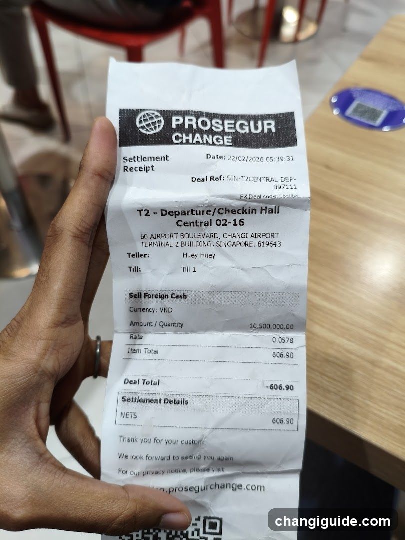 A hand holding a receipt from Proseguor Change, showing details of a foreign currency transaction at Changi Airport in Singapore. The receipt includes settlement date, deal reference, teller name, and transaction amount.