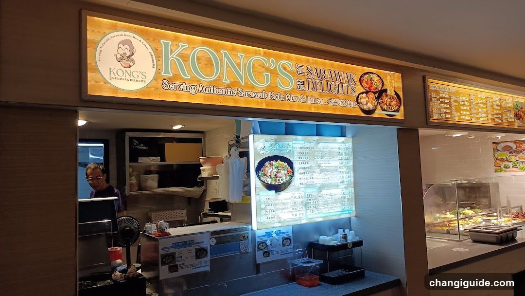 A food stall with a wooden signboard displaying 'KONG'S SARAWAK DELIGHTS' and images of dishes. Inside, there is a menu board showing various food items and prices. A staff member is visible behind the counter.