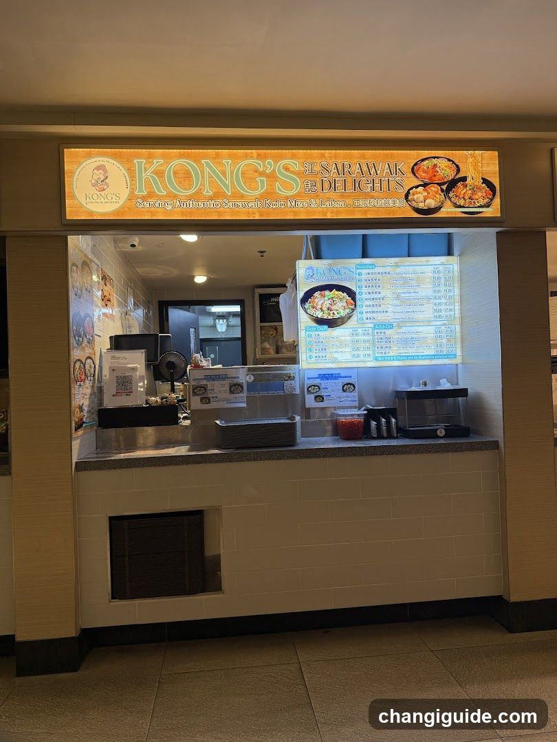 A food stall with a brightly lit sign reading 'KONG'S SARAWAK DELIGHTS' featuring images of dishes like noodles and rice. The counter displays various items including condiments, a menu board listing prices in Chinese characters, and kitchen equipment visible behind the glass.