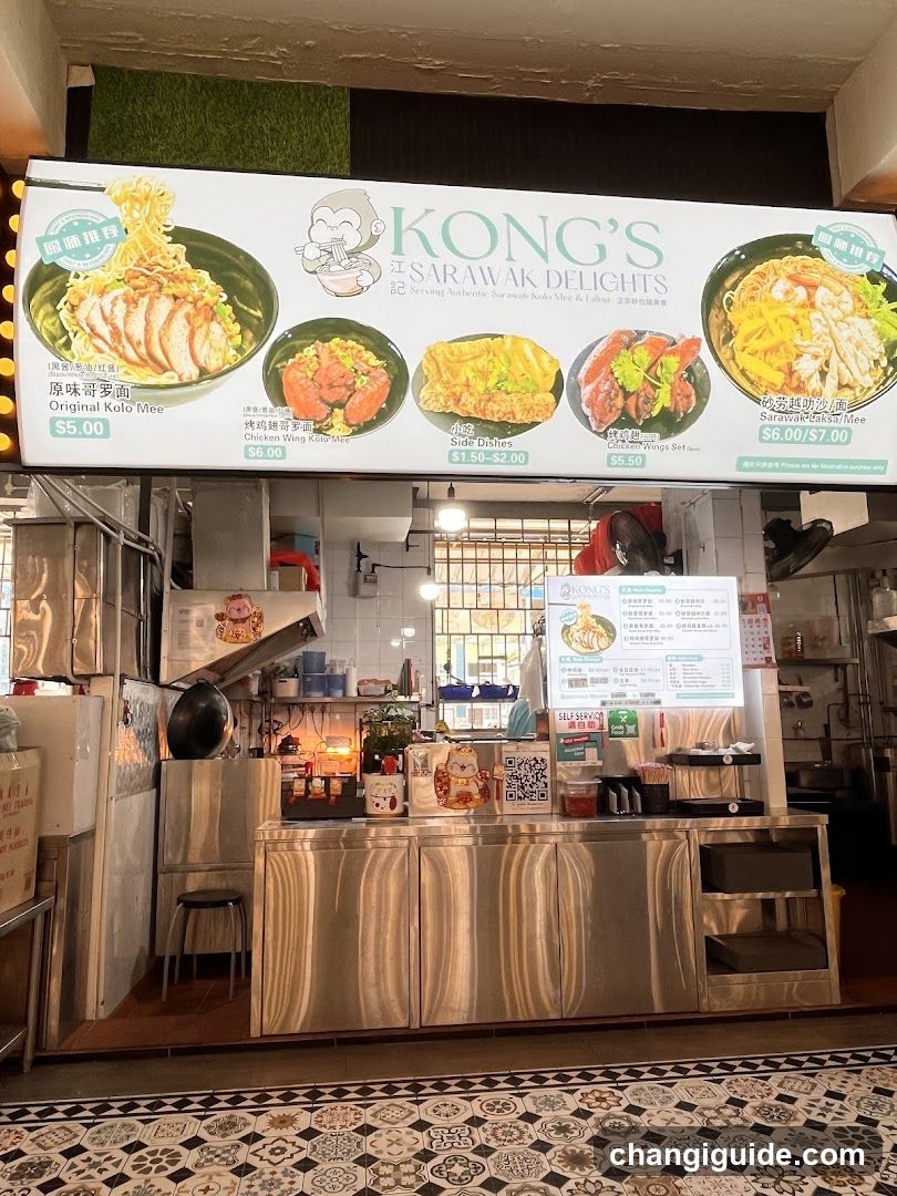 A food stall with a large menu board displaying various dishes like Original Kolo Mee, Charcoal BBQ Pork, Fried Rice, and Spicy Chicken Wings. The interior shows stainless steel counters, cooking equipment, and a tiled floor.