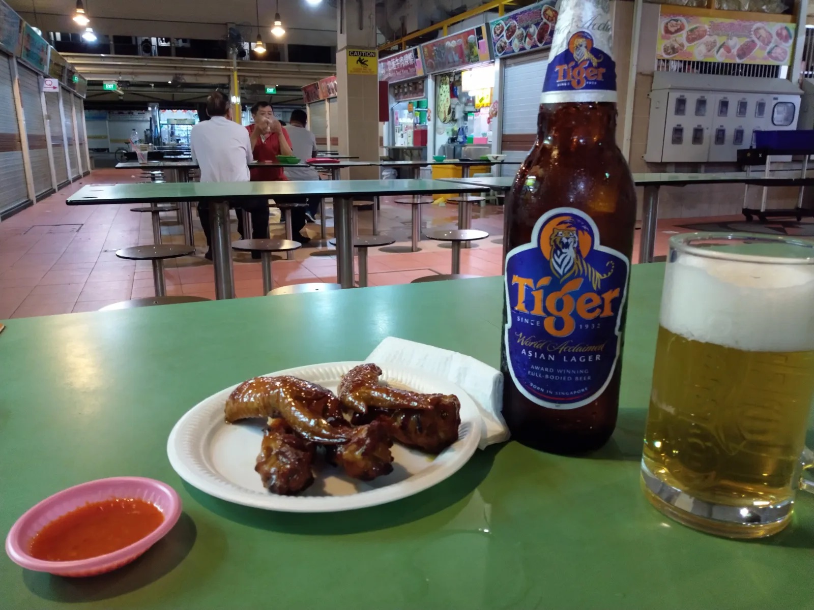 Fried chicken wings, Tiger beer and a green table inside Changi Village Hawker Centre