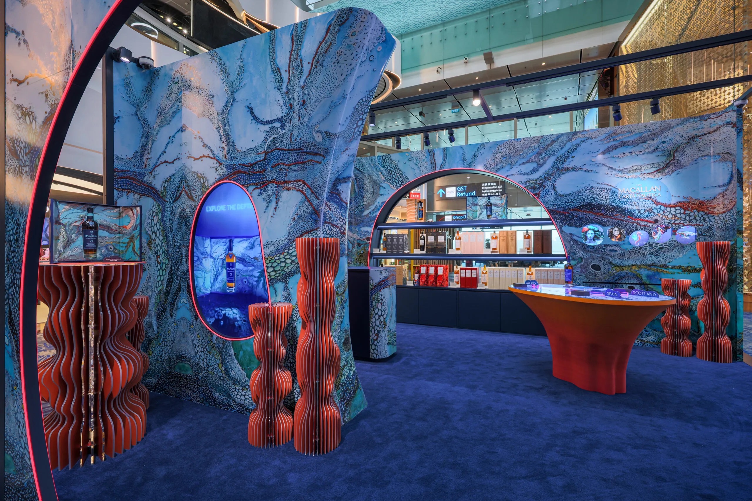 Interior of The Macallan Carta Nautica pop-up in Changi Terminal 3 departure transit, with Explore the Depths display and coral-coloured stands